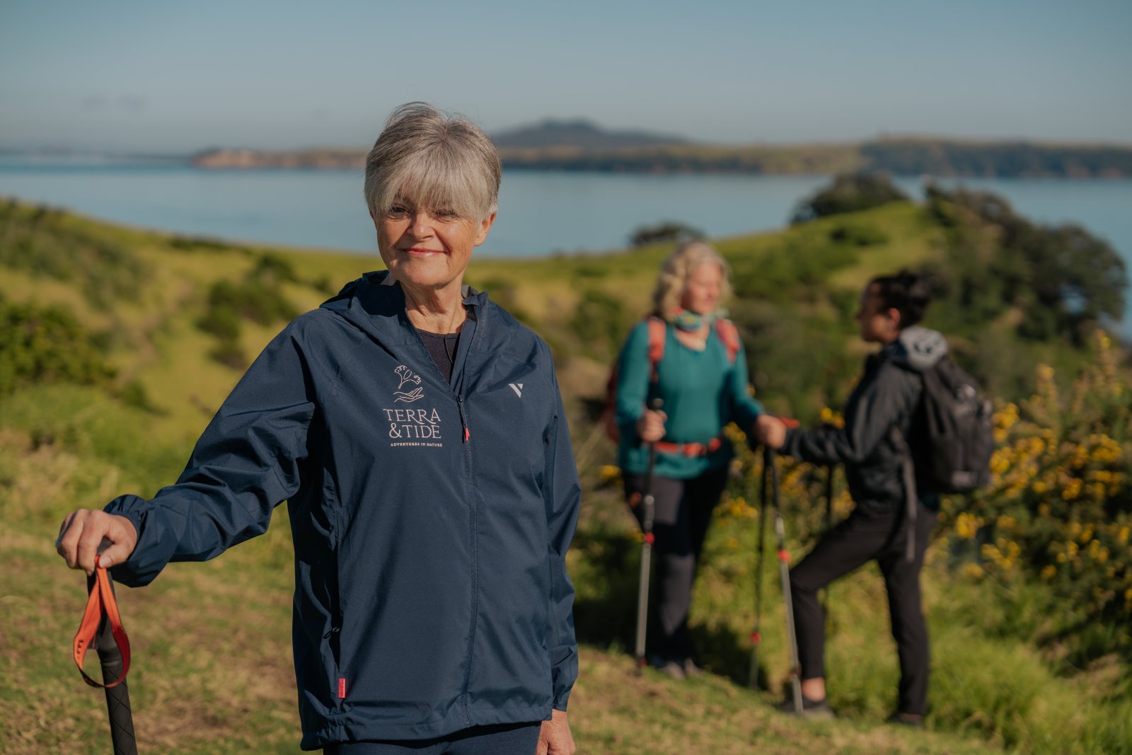 Gabrielle Young, founder of Terra & Tide, on a guided walk on Waiheke Island with the Hauraki Gulf behind her
