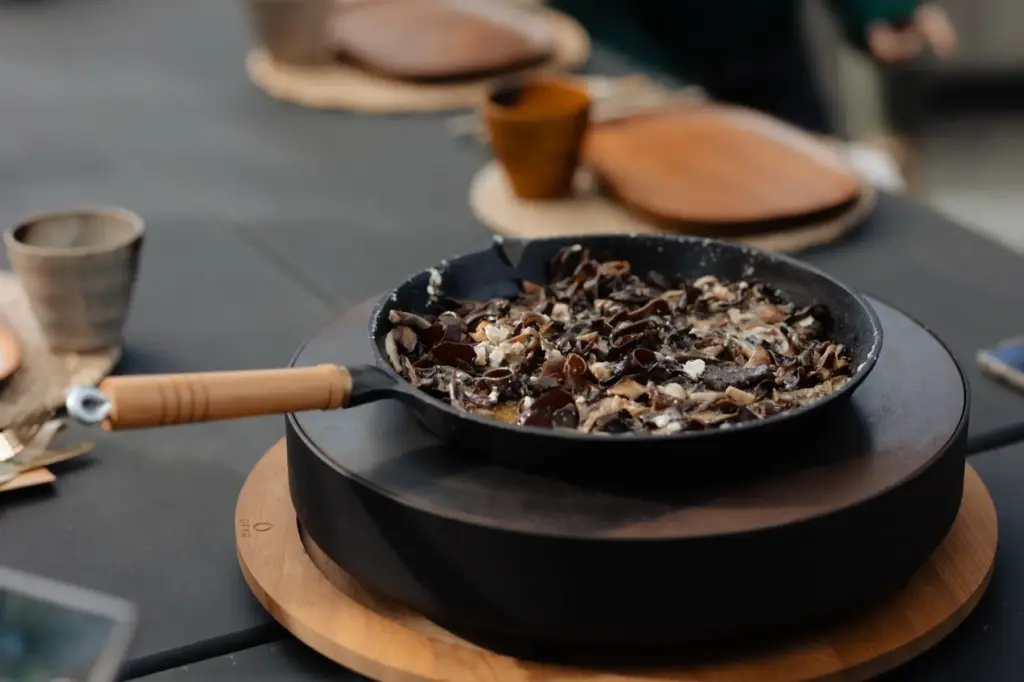 Foraged mushrooms cooking in a skillet over the fire at Velskov